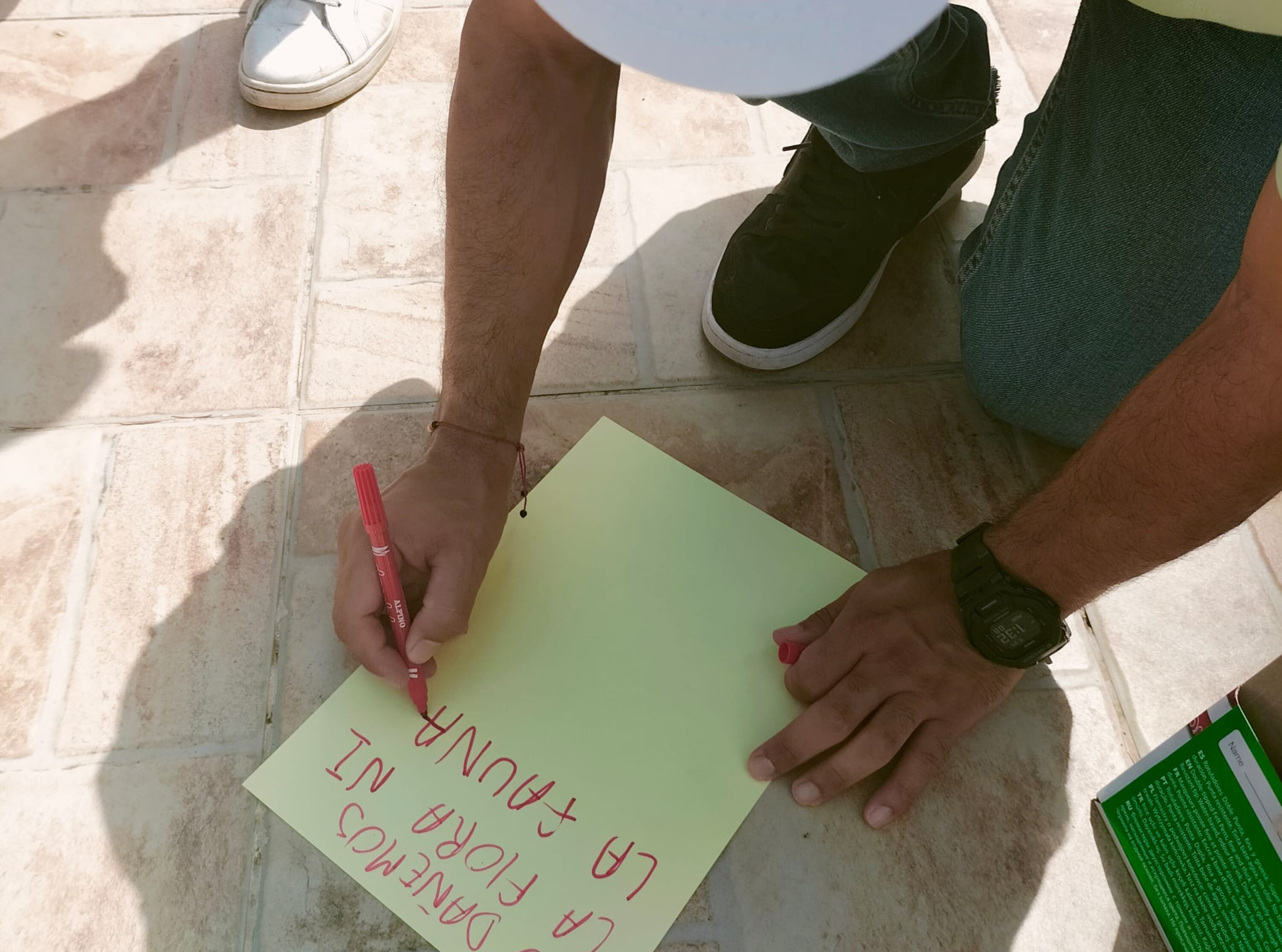 A summer camp participant writes a note while bending over.